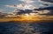 Dramatic panorama seascape shot of a lonely tanker silhouette in wavy blue ocean at a beautiful yellow orange sunset on a cloudy