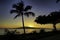 Dramatic photo of ocean, palm trees and Lanai from a beach on Maui at sunset.