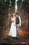 Dramatic picture bride and groom on the background of leaves forest backlight