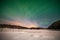 Dramatic polar lights, Aurora borealis with many clouds and stars by moonlight on the sky over a frozen lake and snowy forest in