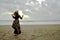 Dramatic portrait of long haired lady in floral formal dress on a stormy beach in front of the sun