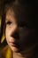Dramatic portrait of  sad little child girl with tear on the cheek  and shadow on face. lonely in dark. Childhood and problems of