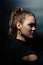 Dramatic portrait of young beautiful girl in profile on dark background. Vertical studio photo of Caucasian model.