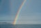 Dramatic rainbow forms over the wake of a cruise ship at sea