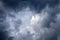 Dramatic ring of black, grey and blue Fractus storm clouds framing blue sky and a white cumulonimbus cloud