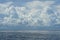 Dramatic scene of powerful white cloud, shades of blue sky background and deep blue sea with ocean water ripple