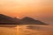 Dramatic scene of sunrise with , sea , mountain , orange sun and boat