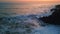 Dramatic sea foaming shoreline stones sunset. Stormy ocean swell crashing rocks