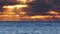 Dramatic sea sunset. Burning sky and shining waves. Warm clouds and pure ocean water at sunrise. Blue and orange colours