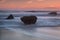 Dramatic seascape blurry waves. Stones during sunset.