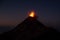 Dramatic shot of a volcanic eruption, with a cloud of ash and lava rising from the summit at night