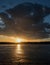 Dramatic sky with cloud over ice covered lake during thaw, reflection of sunset on ice