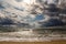 Dramatic sky on a morning seascape. Storm on sandy sea beach.