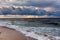 Dramatic sky on a morning seascape. Storm on sandy sea beach.