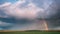 Dramatic Sky During Rain With Rainbow On Horizon Above Rural Landscape Field. Agricultural And Weather Forecast Concept