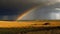 A dramatic sky with rolling storm clouds and a rainbow in the distance created with Generative AI