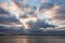 Dramatic sky with sunbeams through the clouds over lake with houses on the shore