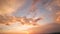 Dramatic sky at sunset with puffy clouds lit by orange setting sun.