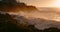 Dramatic stormy ocean waves crash on rocky coastline in Puerto Santiago town at golden sunset in slow-motion. Sea water