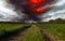 Dramatic stormy sky over a green field and dirt road