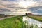 Dramatic sunbeams over farmhouse and river