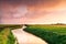 Dramatic sunrise over canal in farmland