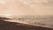 Dramatic sunrise over the ocean. Sandy coast of Oahu island, Hawaii. People walk along the beach. A ray of the sun