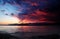 Dramatic sunset in Gelendzhik Bay. The sea and the beach in the foreground, the sun sets in the mountains