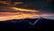 Dramatic sunset sky with illuminated clouds in the mountains. Dark black silhouette of mountain ridge and Jested transmitter tower