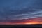 Dramatic sunset or sunrise in orange and blue over open field