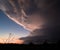 Dramatic sunset in Texas with a looming dark cloud illuminated by golden lightning flashes