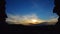 Dramatic sunset with wind blown winter clouds above medieval Hrusov castle, silhouette of castle windows framing the landscape.