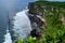 Dramatic vertical sea cliffs, with vast ocean expanse, white waves crashing on the beach