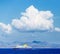 Dramatic view of cruise ship with massive white cloud and blue sky