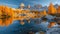 Dramatic view of reflection lake with golden larch trees in Dolomites mountains