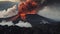 A dramatic volcanic landscape with lava flowing and plumes of smoke rising into the s