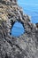 Dramatic volcanic rock formation, blue and turquois water, sunny summer day