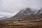 Dramatic Winter landscape image of white cottage at foot of Stob Dearg Buachaille Etive Mor peak in Scottish Highlands