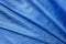 Draped crumpled silk of cobalt blue color background. Texture of folded coral blue shiny silk cloth. Design element of elegant