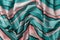 Draped striped fabric of teal and orange colors background. Texture of folded thin cotton cloth with light and dark horizontal