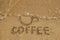 Drawing a cup washed away by a wave and inscription Coffee on the wet sand, top view. Healthy lifestyle concept.