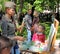 Drawing girl in forage cap with easel in the public garden