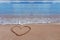 A drawing of a heart as a love symbol on a yellow sand at sea