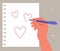 drawing hearts in a notebook, a love message, a woman`s hand with a red marker draws