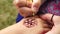 Drawing mehndi on the hand of a little girl closeup outdoors