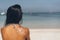 Drawing of a sun with sun protection cream in the shoulder back of a tanned woman in the beach