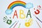 Drawn abbreviation ABA Applied behavior analysis, rainbow, palm prints and paintbrushes on white paper, flat lay