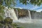 Dray Nur waterfall, against a background of green vegetation, blue sky and clouds