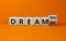 Dream small or big symbol. Turned wooden cubes and changed words `dream small` to `dream big`. Beautiful orange background, co