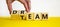 Dream team symbol. Businessman turns cubes and changes the word `dream` to `team`. Beautiful yellow table, white background.